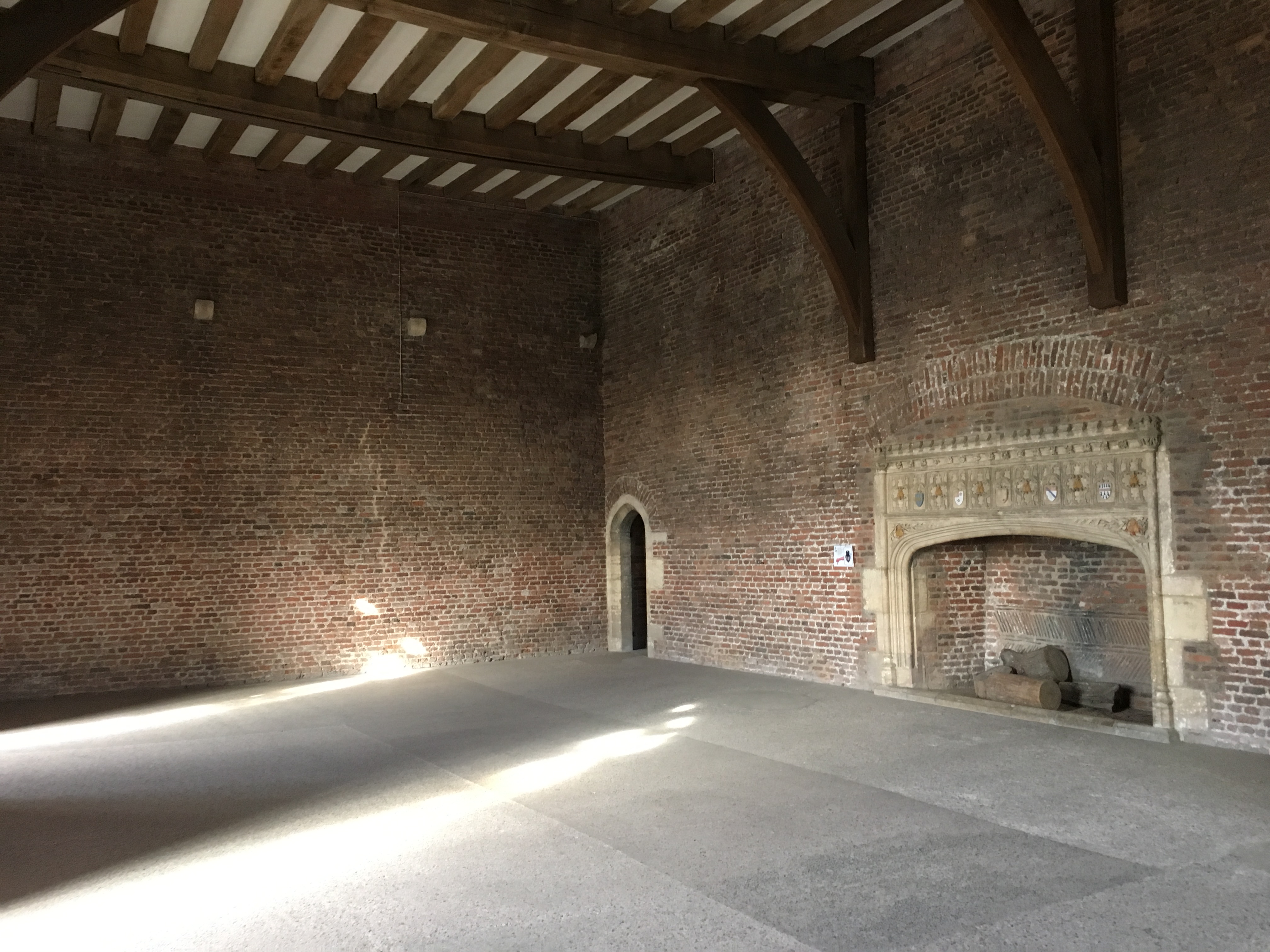 An internal room built of Tudor red-brick with a large central Tudor fireplace.