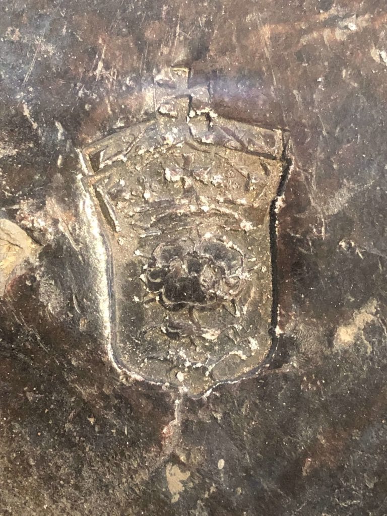 An ingot of lead with the stamp of a Tudor rose and crown above it.