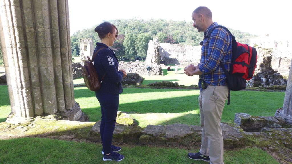 Two people in conversation looking at the ruins of a medieval sacristy